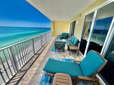 a balcony with chairs and tables and the ocean at Tropic Winds 1401 in Panama City Beach