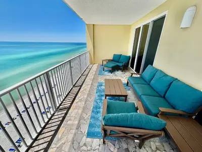 a balcony with a couch and chairs and the ocean at Tropic Winds 1401 in Panama City Beach