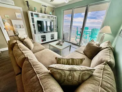 a living room with a large couch and a large window at Tropic Winds 2209 in Panama City Beach