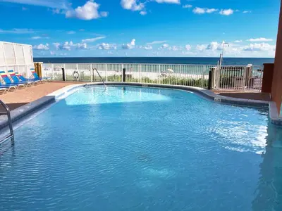 a large swimming pool with the ocean in the background at Tropic Winds 1901 in Panama City Beach