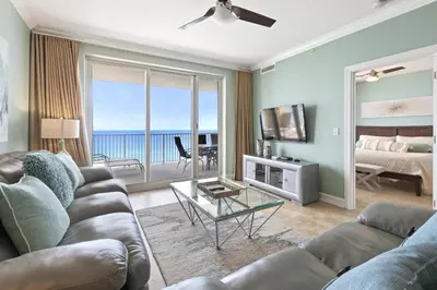 a living room with a couch and a television and the ocean at Ocean Reef 1101 in Panama City Beach