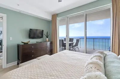 a bedroom with a bed and a television and a balcony at Ocean Reef 1101 in Panama City Beach