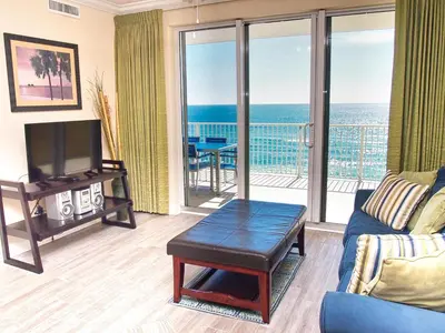a living room with a couch and a tv and a balcony at Tropic Winds 801 in Panama City Beach