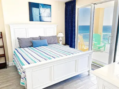 a bedroom with a bed and a balcony with the ocean at Tropic Winds 801 in Panama City Beach