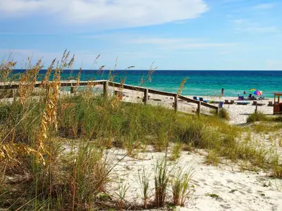 a beach with a wooden fence and the ocean at Ocean Reef 604 in Panama City Beach