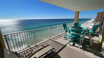 two chairs and a table on a balcony with the ocean at Tropic Winds 1609 in Panama City Beach