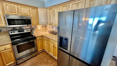 a large stainless steel refrigerator in a kitchen with wooden cabinets at Tropic Winds 1609 in Panama City Beach