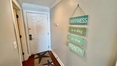 a hallway with a sign that reads happiness is a day at the beach at Tropic Winds 1609 in Panama City Beach