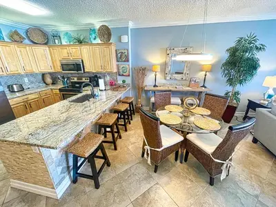 a kitchen with a table and some chairs and a counter at Tropic Winds 1406 in Panama City Beach