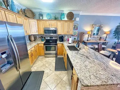 a kitchen with wooden cabinets and stainless steel appliances at Tropic Winds 1406 in Panama City Beach