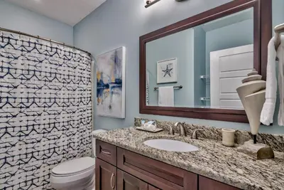 a bathroom with a sink and a toilet and a mirror at Tropic Winds 703 in Panama City Beach