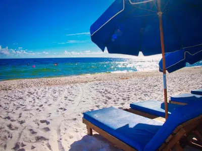 a blue umbrella and chairs on a beach at Tropic Winds 703 in Panama City Beach