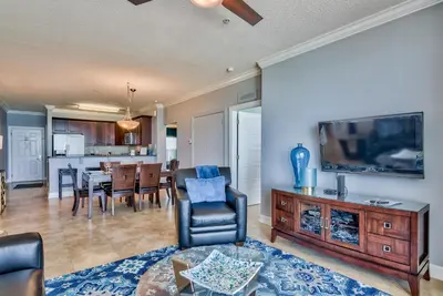 a living room with a tv and a dining room at Tropic Winds 703 in Panama City Beach