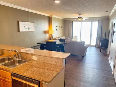 a kitchen with a sink and a living room at Ocean Reef 1308 in Panama City Beach