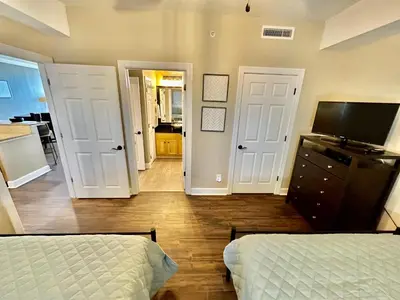 a bedroom with two beds and a dresser and two doors at Ocean Reef 1308 in Panama City Beach