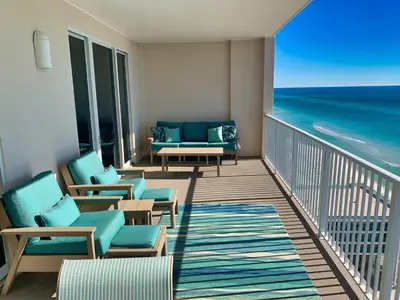 a balcony with chairs and a couch and the ocean at Ocean Reef 1604 in Panama City Beach