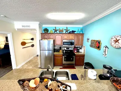 a kitchen with blue walls and wooden cabinets at Ocean Reef 1402 in Panama City Beach