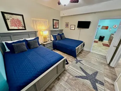 a bedroom with two blue beds and a television at Ocean Reef 1402 in Panama City Beach