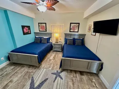 a bedroom with two beds and a flat screen tv at Ocean Reef 1402 in Panama City Beach