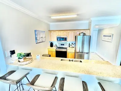 a kitchen with a counter and chairs in a room at Ocean Reef 1107 in Panama City Beach