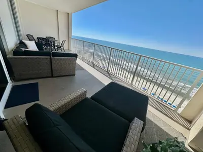a living room with a couch and a balcony with the ocean at Ocean Reef 1107 in Panama City Beach