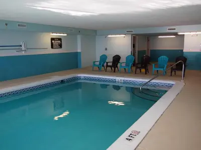 a swimming pool with chairs and a table in a room at Ocean Reef 1007 in Panama City Beach
