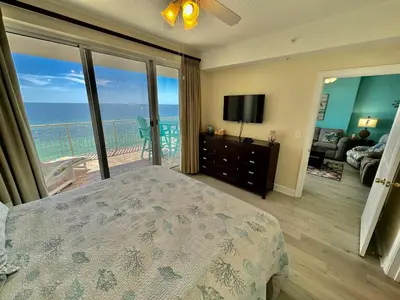 a bedroom with a bed and a balcony with the ocean at Ocean Reef 1007 in Panama City Beach
