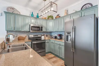 a kitchen with blue cabinets and a stainless steel refrigerator at Tropic Winds 1909 in Panama City Beach
