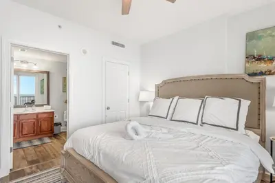 a white bedroom with a large bed and a bathroom at Tropic Winds 1909 in Panama City Beach