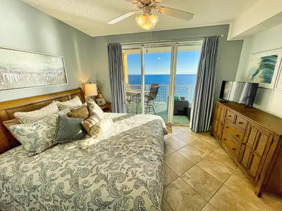 a bedroom with a bed and a view of the ocean at Tropic Winds 1605 in Panama City Beach