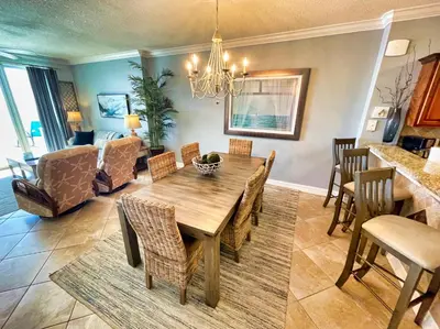 a dining room and living room with a table and chairs at Tropic Winds 1605 in Panama City Beach