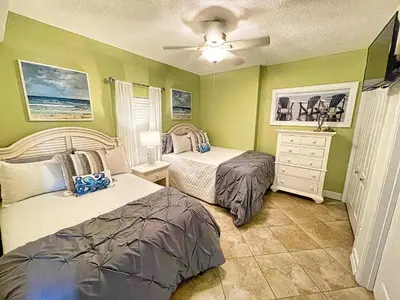 two beds in a bedroom with green walls at Tropic Winds 1605 in Panama City Beach