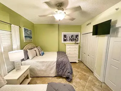 a bedroom with two beds and a flat screen tv at Tropic Winds 1605 in Panama City Beach