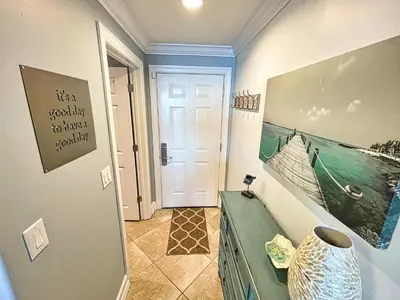 a hallway with a door to a room with a vase at Tropic Winds 1605 in Panama City Beach