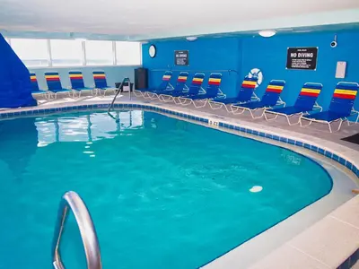 a swimming pool in a hotel room with blue walls and chairs at Tropic Winds 1605 in Panama City Beach