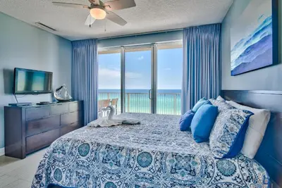 a bedroom with a bed with a view of the ocean at Tropic Winds 707 in Panama City Beach