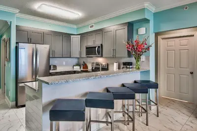 a kitchen with a bar with stools and appliances at Tropic Winds 603 in Panama City Beach