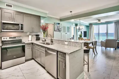 a kitchen with a counter and a dining room at Tropic Winds 603 in Panama City Beach