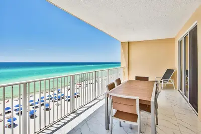 a balcony with a table and chairs and the beach at Tropic Winds 603 in Panama City Beach
