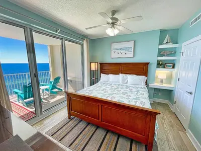 a bedroom with a bed and a balcony with the ocean at Ocean Reef 1808 in Panama City Beach