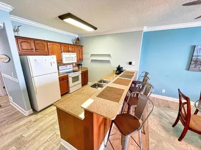 a kitchen with a refrigerator and a table and chairs at Ocean Reef 1808 in Panama City Beach