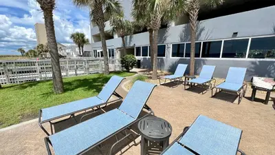 a group of blue chairs and a grill with palm trees at Ocean Reef 1902 in Panama City Beach