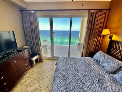 a bedroom with a bed and a television and a balcony at Ocean Reef 1902 in Panama City Beach