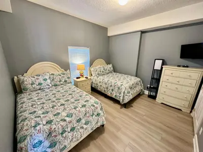 a bedroom with two beds and a dresser and a bed and a dresser at Ocean Reef 1907 in Panama City Beach