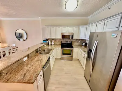 a kitchen with white cabinets and a stainless steel refrigerator at Tropic Winds 1107 in Panama City Beach