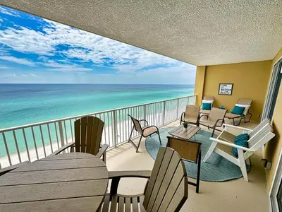 a balcony with chairs and tables and the ocean at Tropic Winds 1107 in Panama City Beach