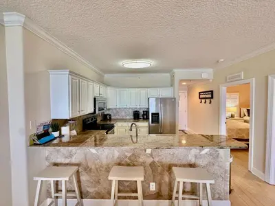 a kitchen with a large counter with two stools at Tropic Winds 1107 in Panama City Beach