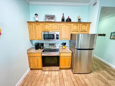 a kitchen with wooden cabinets and a stainless steel refrigerator at Ocean Reef 2103 in Panama City Beach