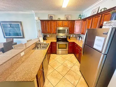 a kitchen with wooden cabinets and a stainless steel refrigerator at Tropic Winds 809 in Panama City Beach