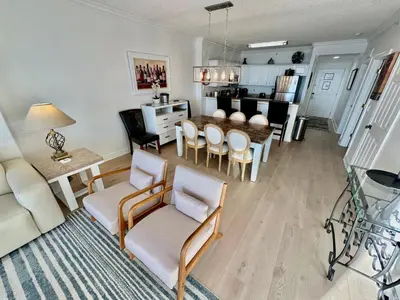 a living room with a table and chairs and a kitchen at Tropic Winds 1201 in Panama City Beach